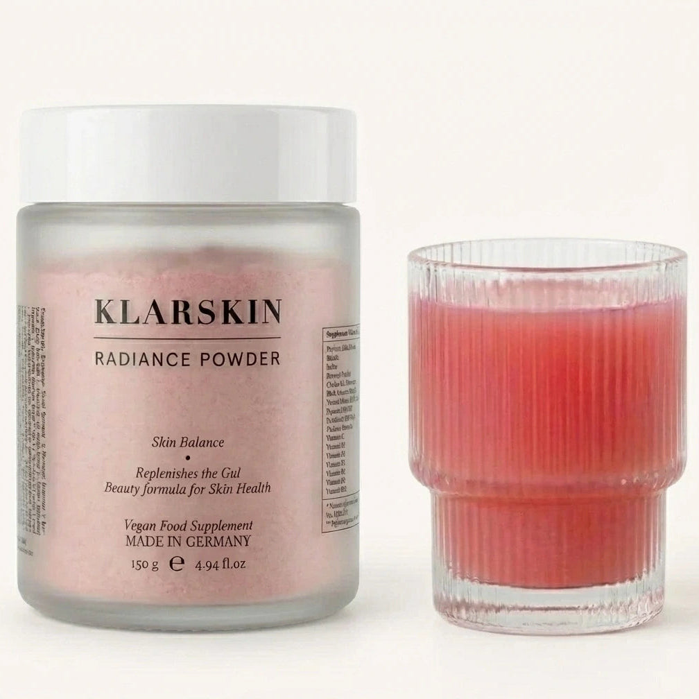 Klarskin Radiance Powder jar and a glass of pink liquid on a white background